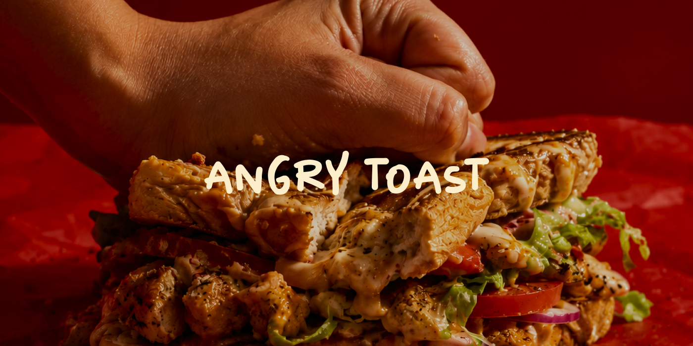 A hand smashing a loaded Angry Toast sandwich, with the wordmark across the middle