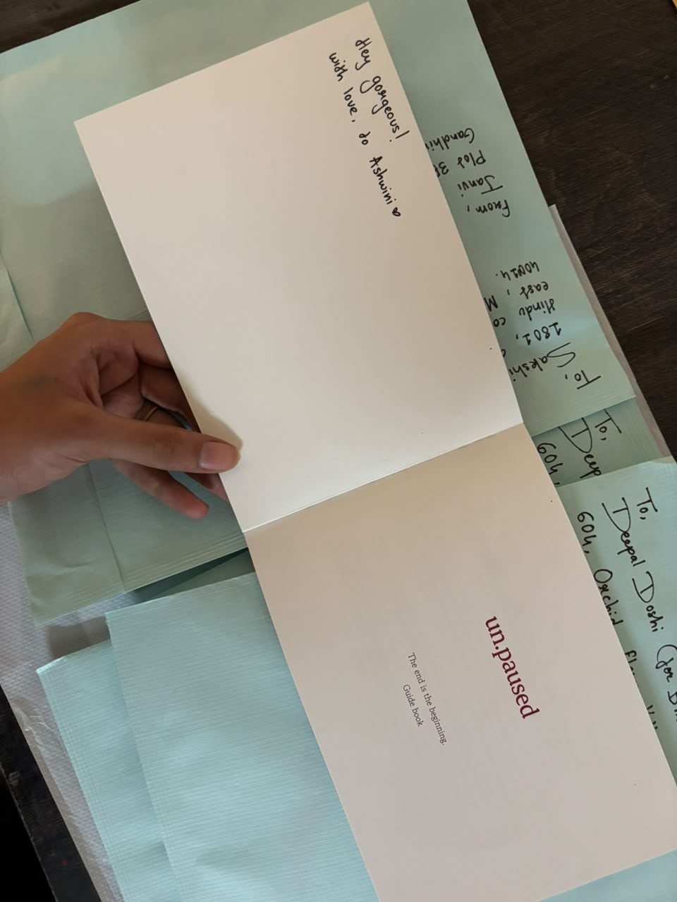 Open un.paused greeting card alongside outgoing envelopes